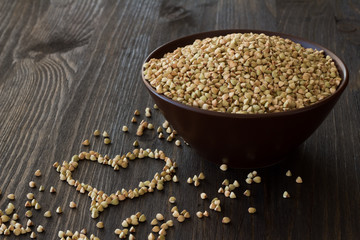 Green buckwheat in ceramic bowl on a wooden surface