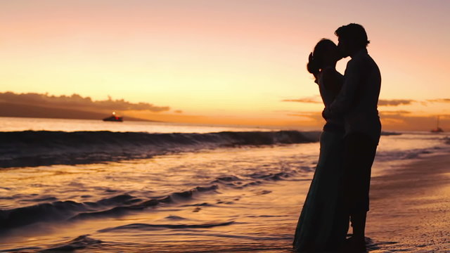 Silhouetted couple kiss at a beautiful sunset. 