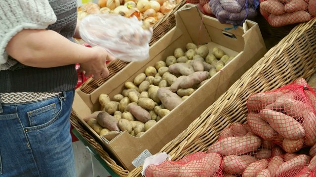 Woman chosing potato shopping in department store uhd