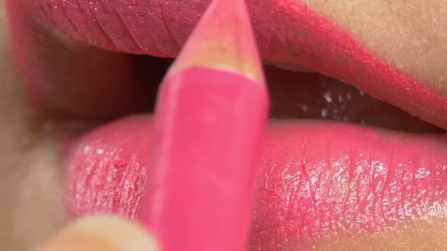 Make-up artist making for beautiful woman pink lipstick