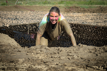 Mud Run CO. crawling in muddy water hole under mesh netting