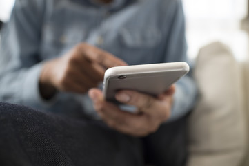 Men are using a smart phone sitting on the sofa