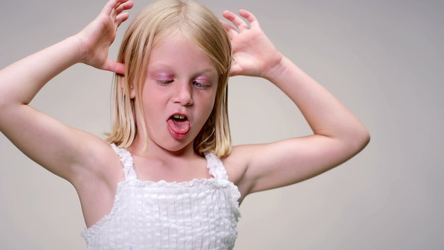Young blonde girl pulls a funny face against a white background