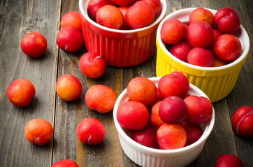 Fresh plum in the colorful bowl on wooden background
