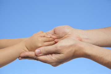 father and son holding hands on sky background