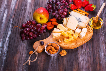 Different types of cheese with fruits, berries, honey and nuts