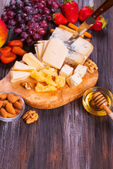 Different types of cheese with fruits, berries, honey and nuts