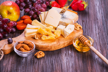 Different types of cheese with fruits, berries, honey and nuts