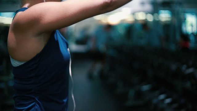 Woman lifting weights at gym, working out her arms