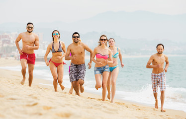 Positive adults running at sandy beach