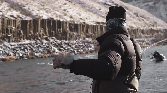 Slow motion shot of a fly fisherman casting out his line and lure