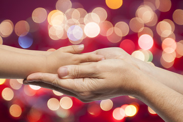 father and son holding hands on christmas lights background