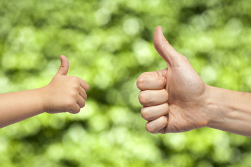 father and son hands giving like on green background