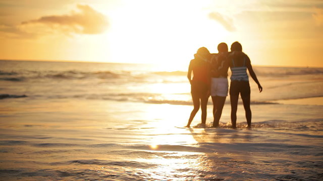 Mother and her daughters stand on the beach and look out over the ocean