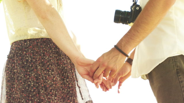 Close up of a young couple holding hands romantically under a tree