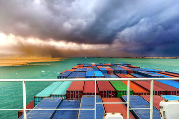 Suez Canal, Egypt. Container ship going through desert storm