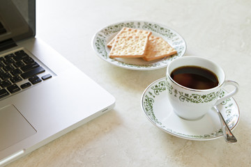 Coffee cup and cracker with laptop on marble table