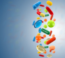 Falling colorful medical pills on blue background
