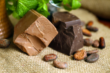 Chunks of chocolate with mint and coffee grains  on burlap cloth, closeup
