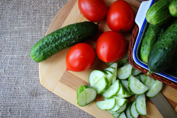 Cucumbers and tomatoes lying on the board and chopped salad..