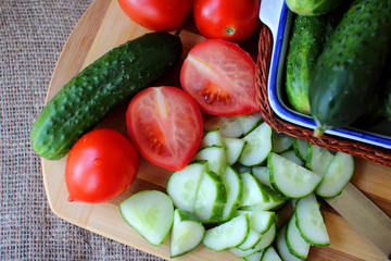 Cucumbers and tomatoes lying on the board and chopped salad..