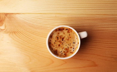 Cup of coffee on wooden table, top view
