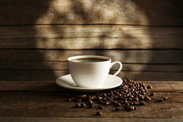 Cup of coffee with grains on wooden background