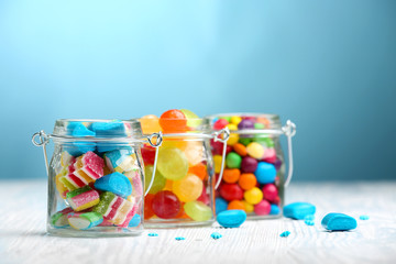 Bunte Bonbons in Gläsern auf dem Tisch auf blauem Hintergrund