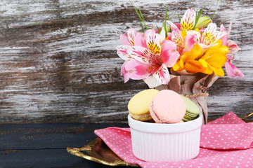 Delicious macaroon with beautiful flowers on wooden background