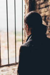 Woman looking through an iron grid at a town below