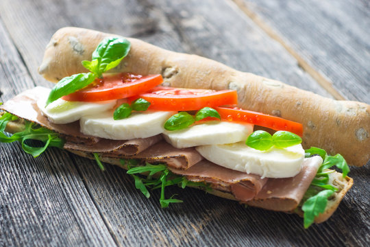 Sandwich with crispy baguette on a wooden background