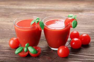 Glasses of tomato juice with vegetables on wooden background