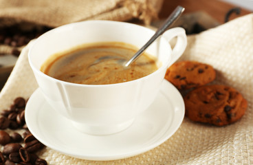 Cup of coffee with cookie on table, closeup
