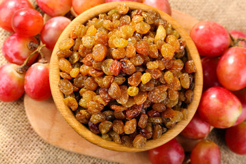 Raisins in bowl with grapes on table close up