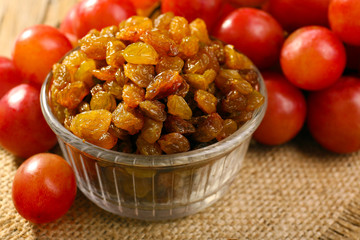 Raisins in bowl with grapes on table close up