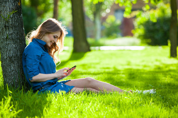 Pretty young caucasian woman  sitting outside under a tree