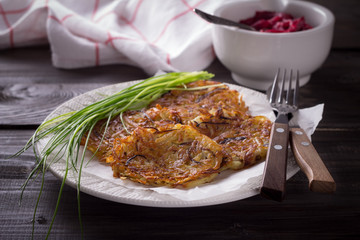 Potato fritters, beet salad, green onions on a wooden surface