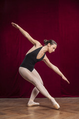young beautiful ballet dancer on red velvet background