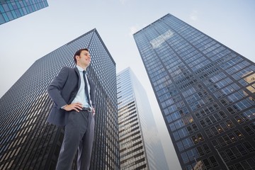 Composite image of happy businessman with hands on hips