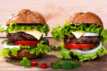 Big hamburger with beef cutlet and vegetables on wood background