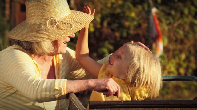 An adorable little girl puts on her grandmother's hat and sticks her tongue out 