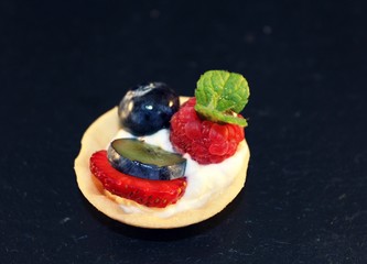 Mini Tartes gefüllt mit Obst auf einem Sahneschaum