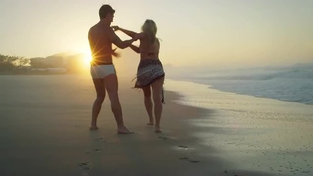 couple have fun on a beach at sunset