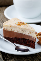 Tasty nuts cake with cup of coffee on wooden background.