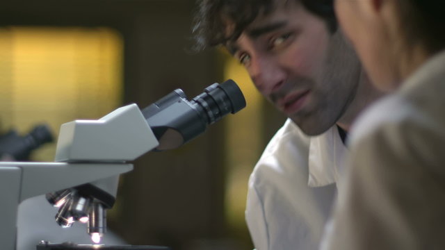 College Students in a lab look through a microscope during their experiments