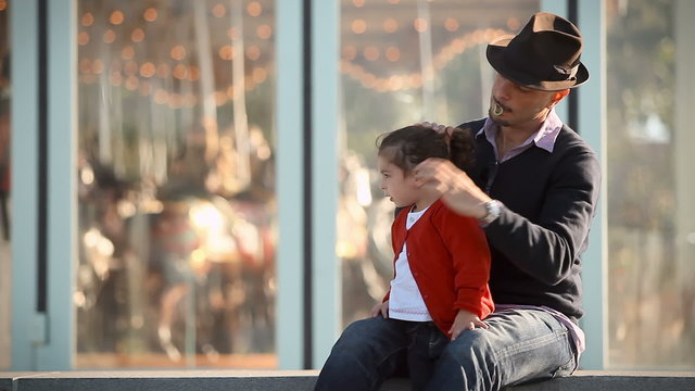 A father ties his daughters hair into a pony tail