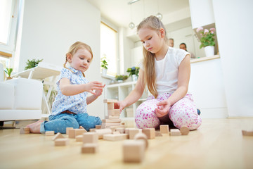 Zwei Kinder bauen Turm aus Bausteinen