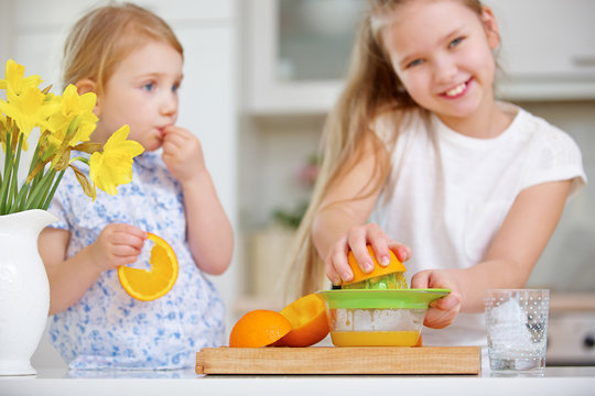 Kinder pressen Orangensaft mit Zitruspresse