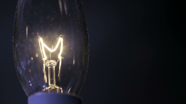 Close up of a candle shaped light bulb in darkness.