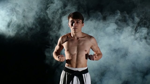 Man training taekwondo or karate with a naked torso and a black